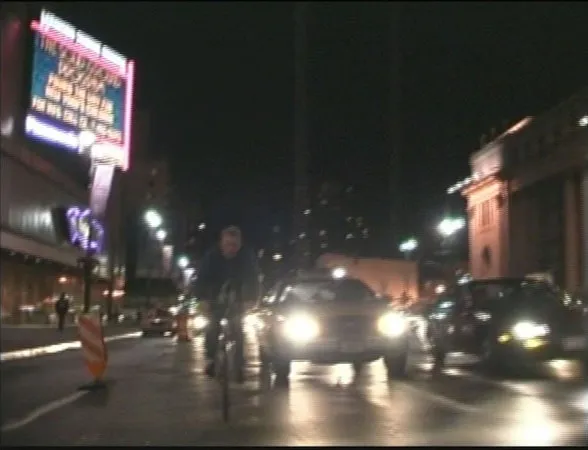 A photo of Van Neistat riding his bike through bumper-to-bumper traffic on a New York City street.