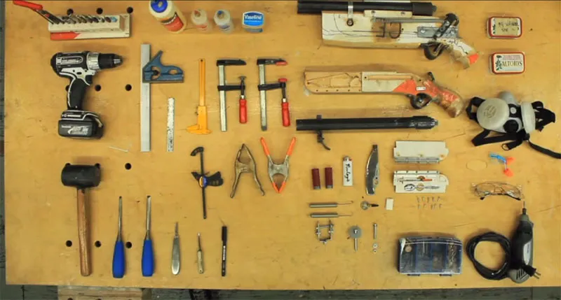 A top-down photo shows 'knolled' items on a workbench's surface inside Tom Sachs' studio.